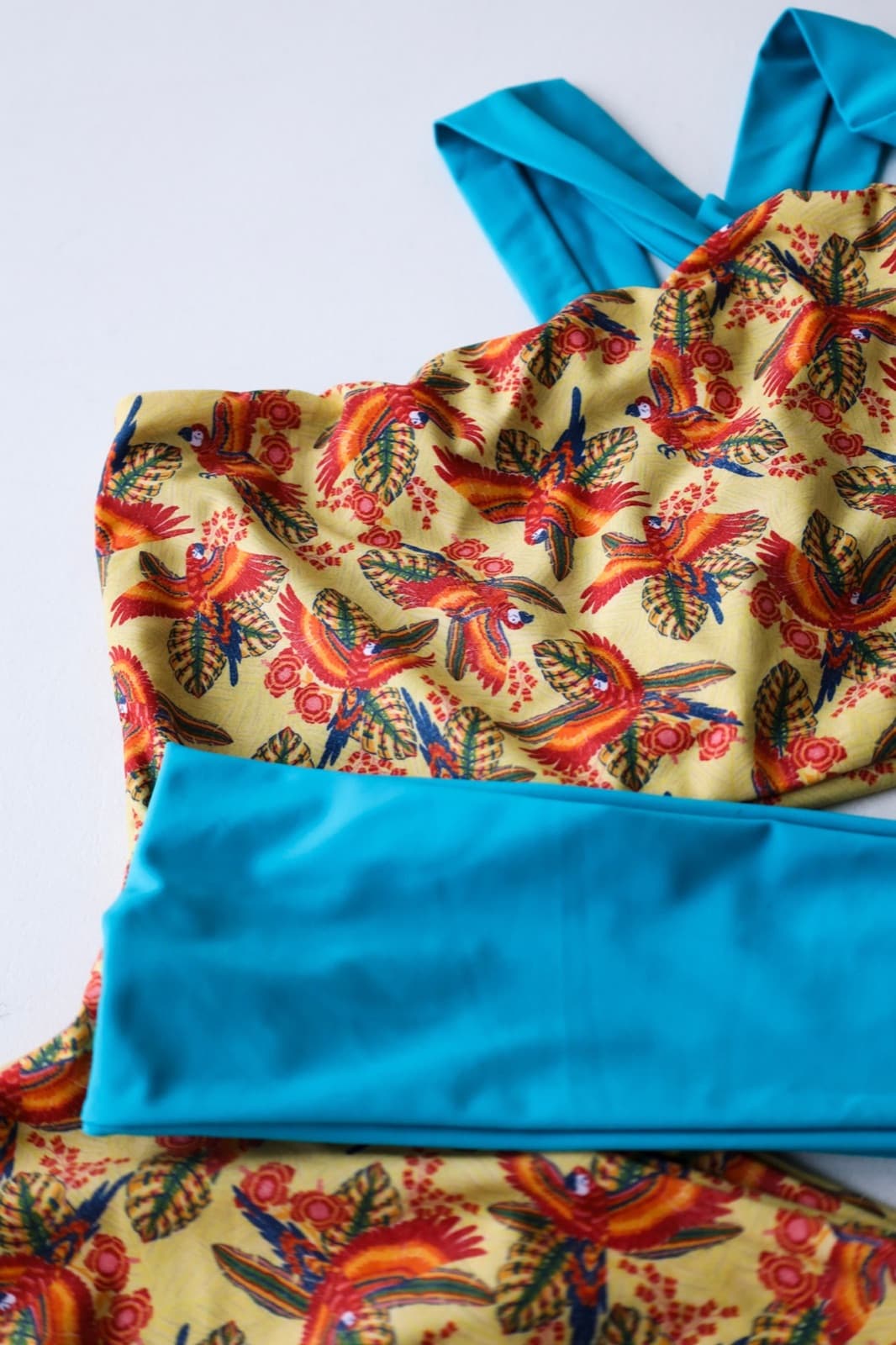 Detalhe do padrão Arara: araras e folhas sobre amarelo, com uma faixa azul